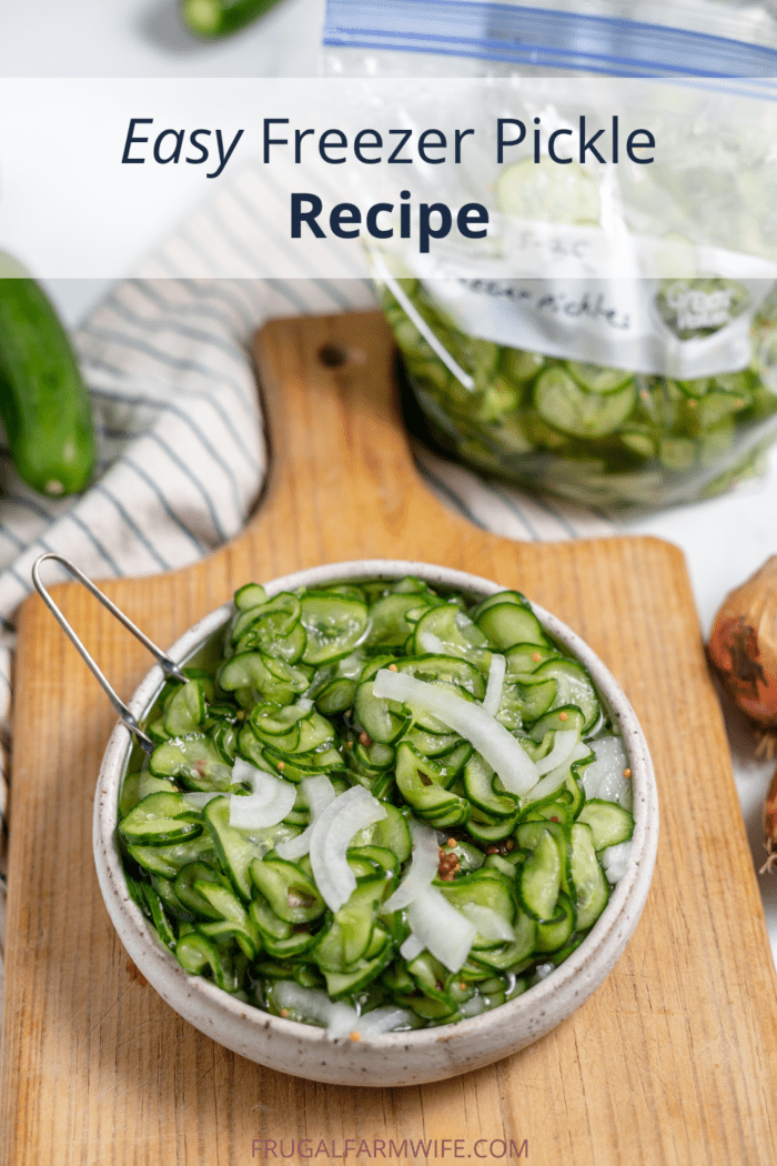 Image shows a small bowl full of homemade freezer pickles sliced, resting on a cutting board. A small tongs rests in the bowl to pick out he pickles. Text box above reads "Easy Freezer Pickle Recipe."