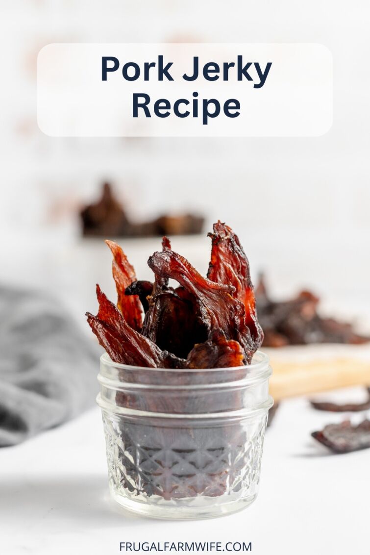Image shows a small glass jar full of pork jerky sitting on a table. Above the jar is text that reads "Pork Jerky Recipe"