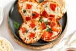 mini pizzas made with english muffins on a plate.